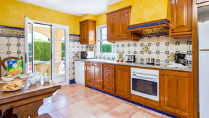 A kitchen with wooden cabinets, a white refrigerator, a stove, and a microwave. There is a dining table with breakfast items. - Villa Marcolis Mar - Four Bedroom Villa, Sleeps 6 (Serpentona)