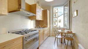 A modern kitchen with wooden cabinets, a gas stove, and a dining area with a table and chairs. - Lauren 2 bedroom apartment VRBO (Nice)