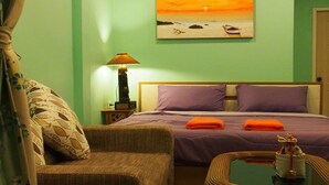 Una habitación con cama, mesita de noche, lámpara, silla y mesa con un adorno.