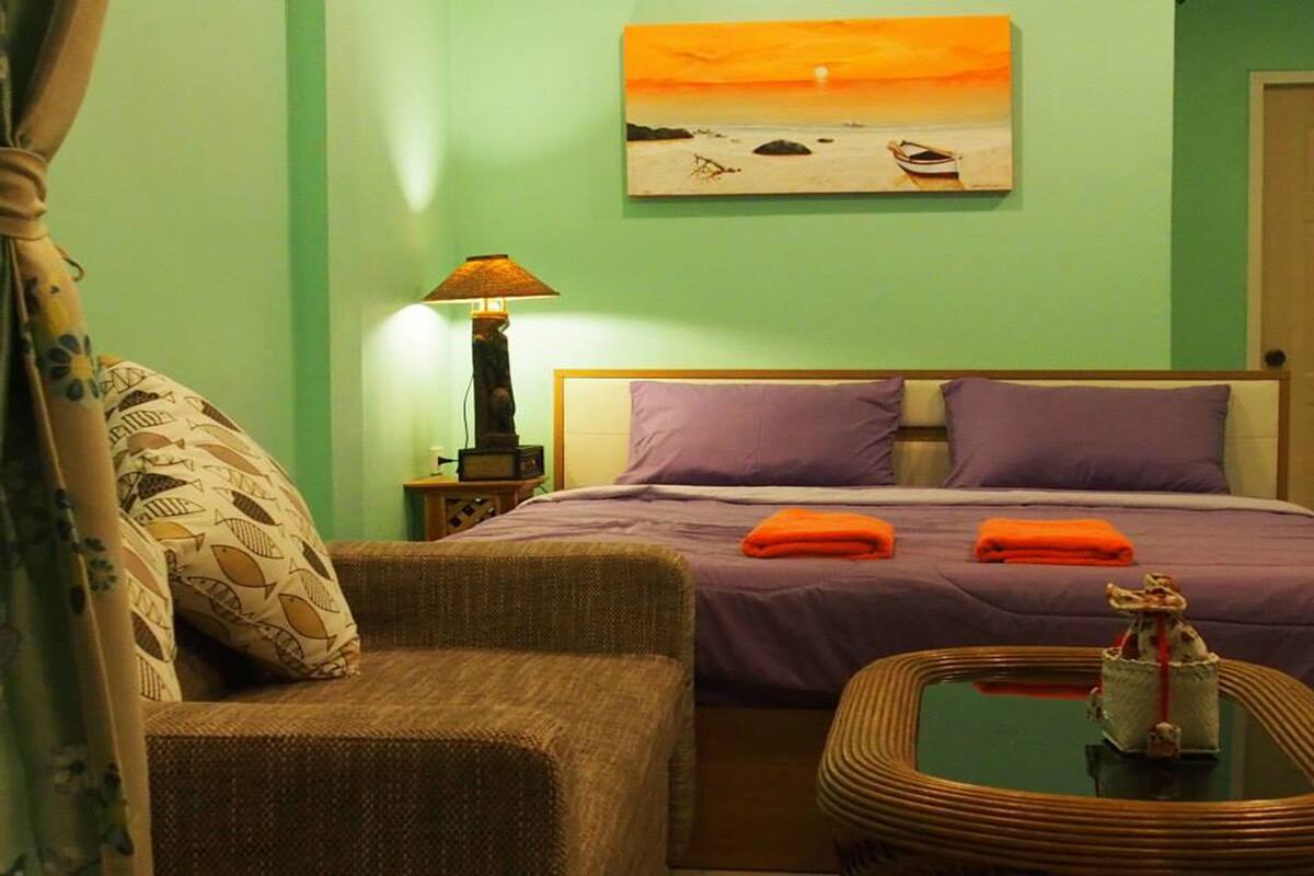 Une pièce comprenant un lit, une table de chevet, une lampe, une chaise et une table ornée d’un objet décoratif.