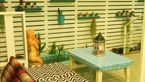 Un espacio exterior acogedor con una mesa de cuadros, un farol y varias plantas en macetas.