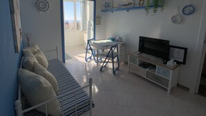 Una sala de estar con un sofá, televisor y una mesa de comedor.