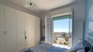 Un dormitorio con cama, armario y balcón con vistas.