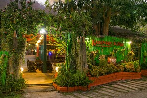 A cozy, well-lit entrance with a green fence and a sign reading "KAREN eco lodge." - Karen Eco Lodge (Mae Wang)