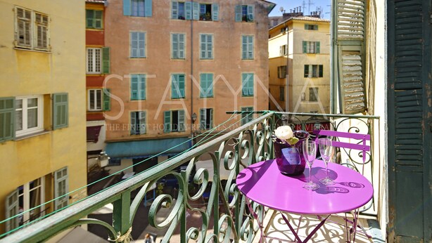 Ein Balkon mit einem lila Tisch, einer Champagnerflasche und zwei Gläsern.