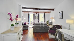 Ein Zimmer mit einem Bett, einem Schreibtisch, einem Stuhl, einer Kommode und einem Fenster mit Vorhängen.