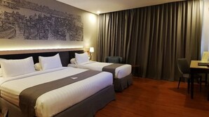 A hotel room with two beds, a desk, a chair, and a large wall mural. - Pyramid Suites (Banjarmasin)