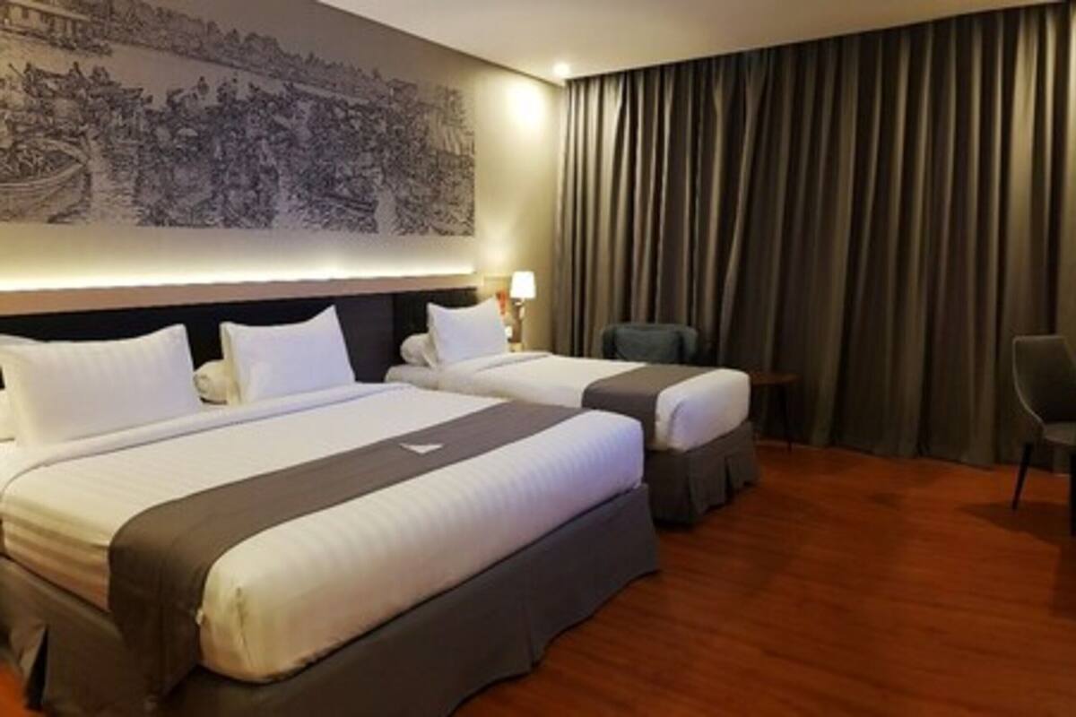 Ein Hotelzimmer mit zwei Betten, einem Schreibtisch, einem Stuhl und einem großen Wandbild.