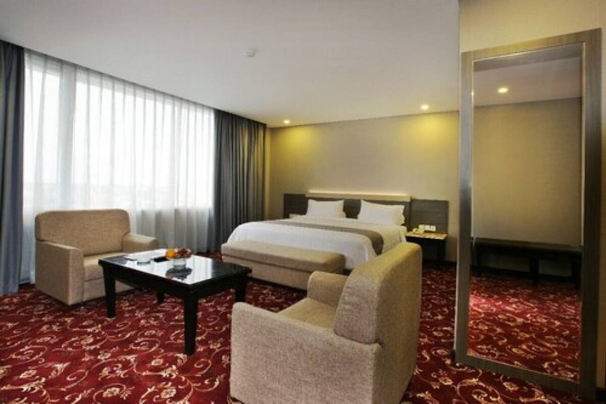 Ein Hotelzimmer mit einem großen Bett, einer Couch, einem Couchtisch und einem Spiegel.