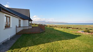Une maison avec une terrasse en bois et vue sur la mer.