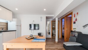 Una cucina moderna con un tavolo di legno, una TV a schermo piatto e un divano in un soggiorno.