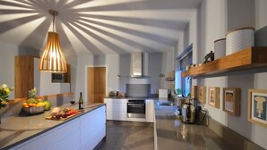 A modern kitchen with a central island, stainless steel appliances, and a pendant light. - Sonas VRBO (Dingle)