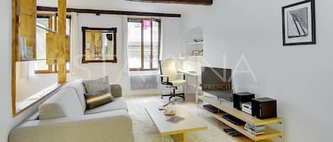 A modern living room with a sofa, coffee table, TV, and a bookshelf.