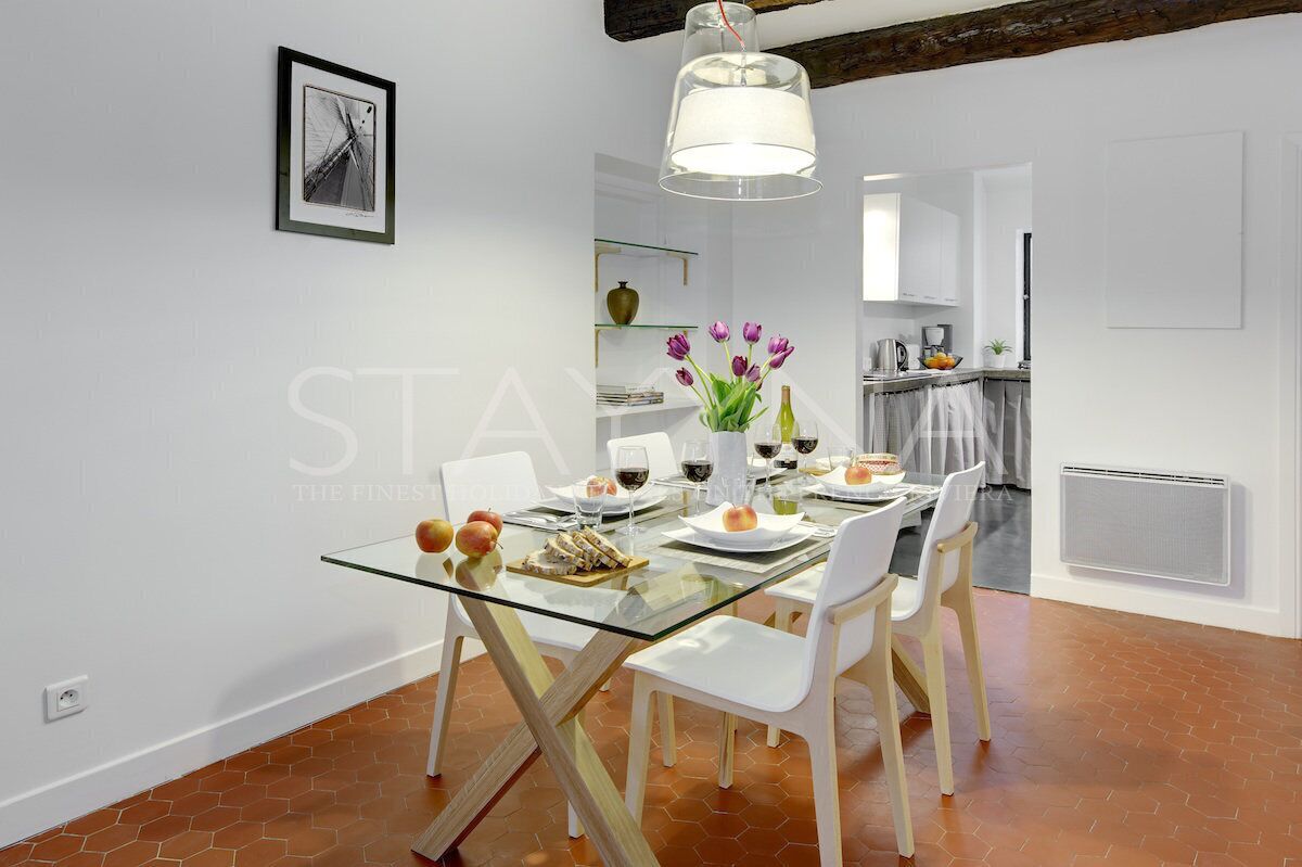 A modern dining area with a glass table, white chairs, and a pendant light.