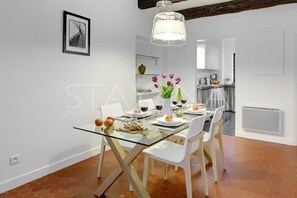 Un comedor moderno con una mesa de vidrio, sillas blancas y una lámpara colgante.
