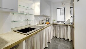Eine moderne Küche mit einer Granit Arbeitsplatte, einem Edelstahl-Spülbecken und weißen Schränken.