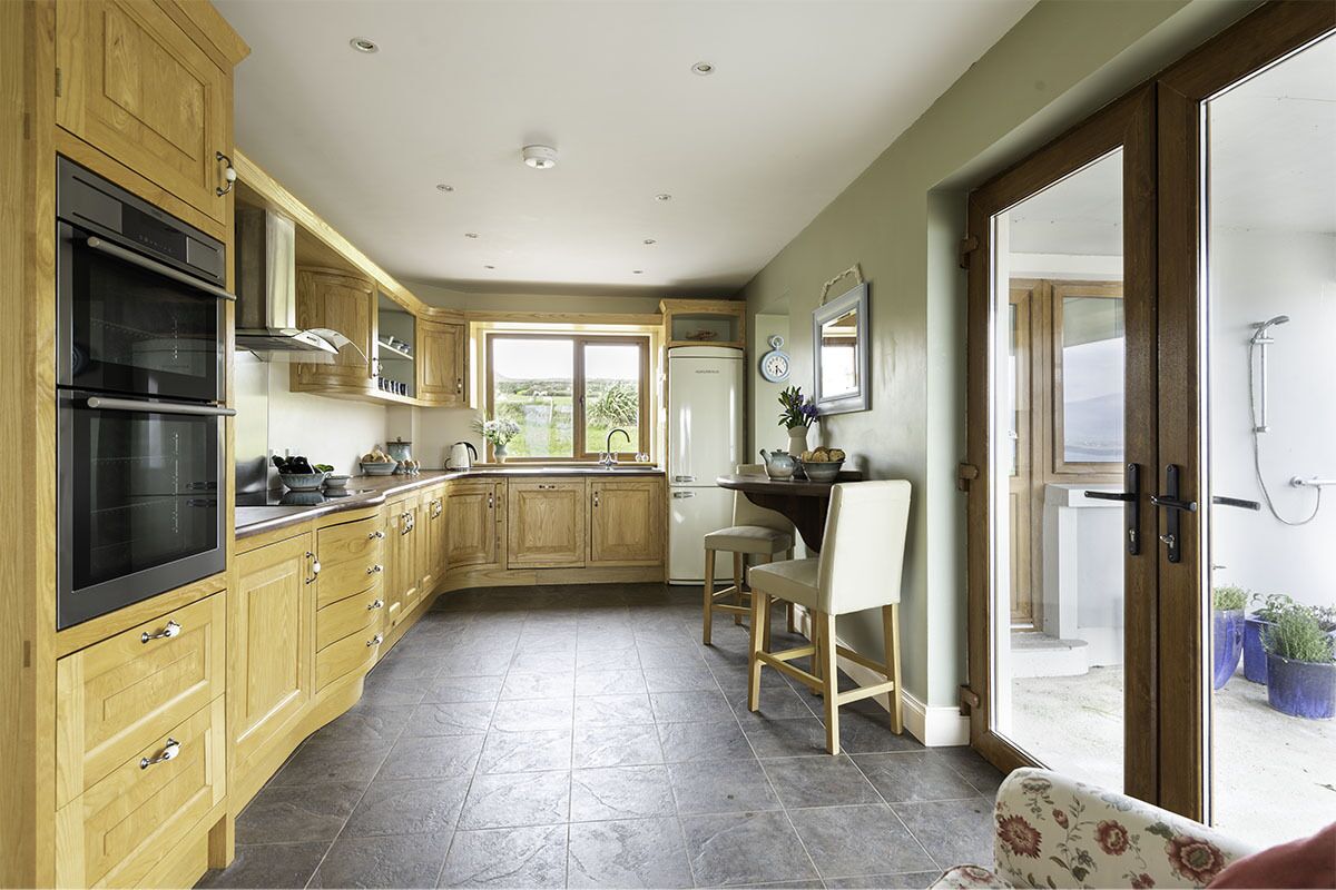A kitchen with wooden cabinets, a built-in oven, and a dining area with a chair and table.