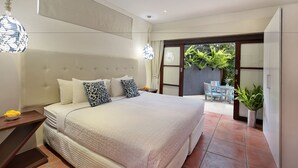 Une chambre dotée d’un grand lit, d’un ventilateur de plafond et offrant une vue sur la terrasse extérieure.