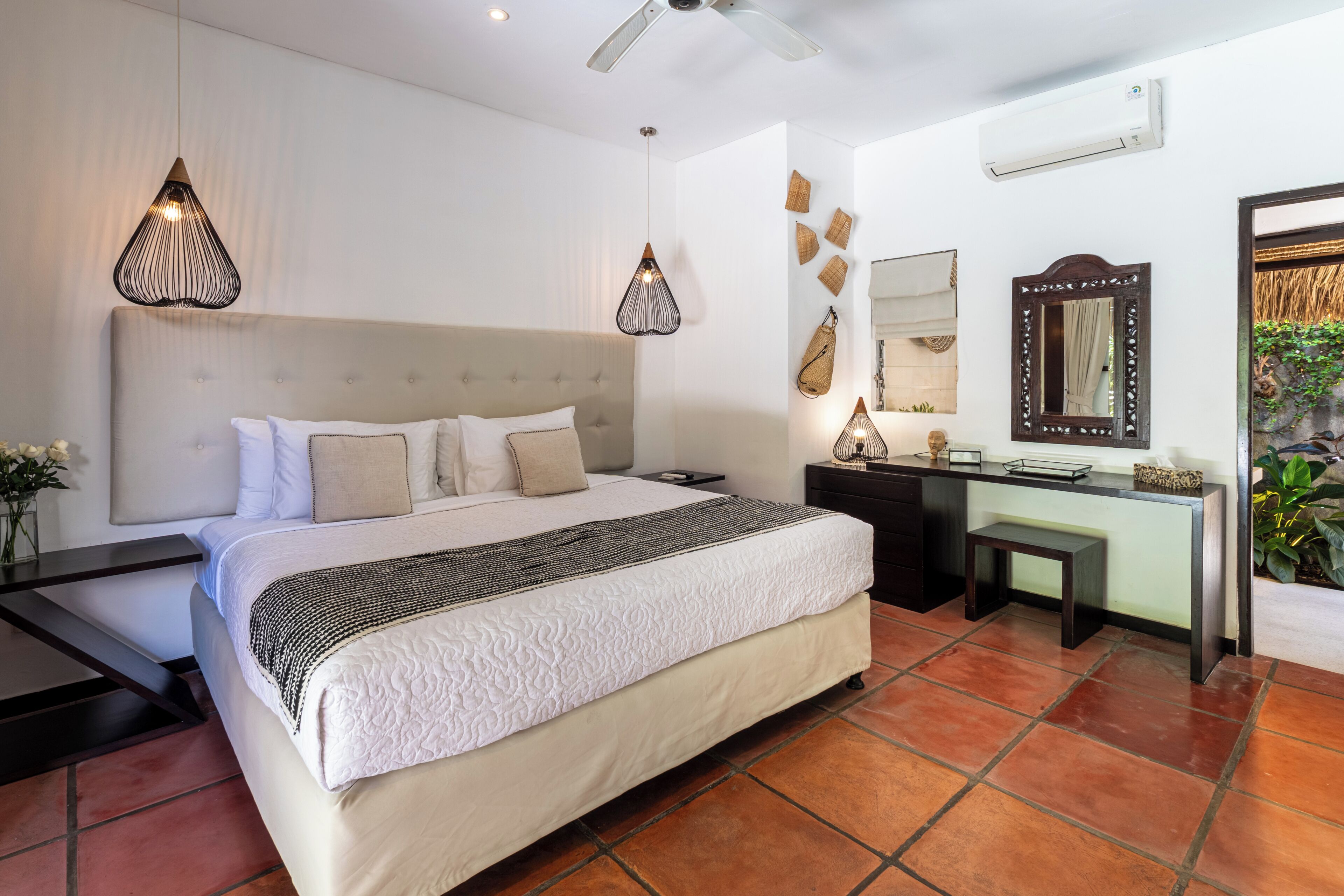 A bedroom with a bed, bedside tables, a desk, and a mirror.