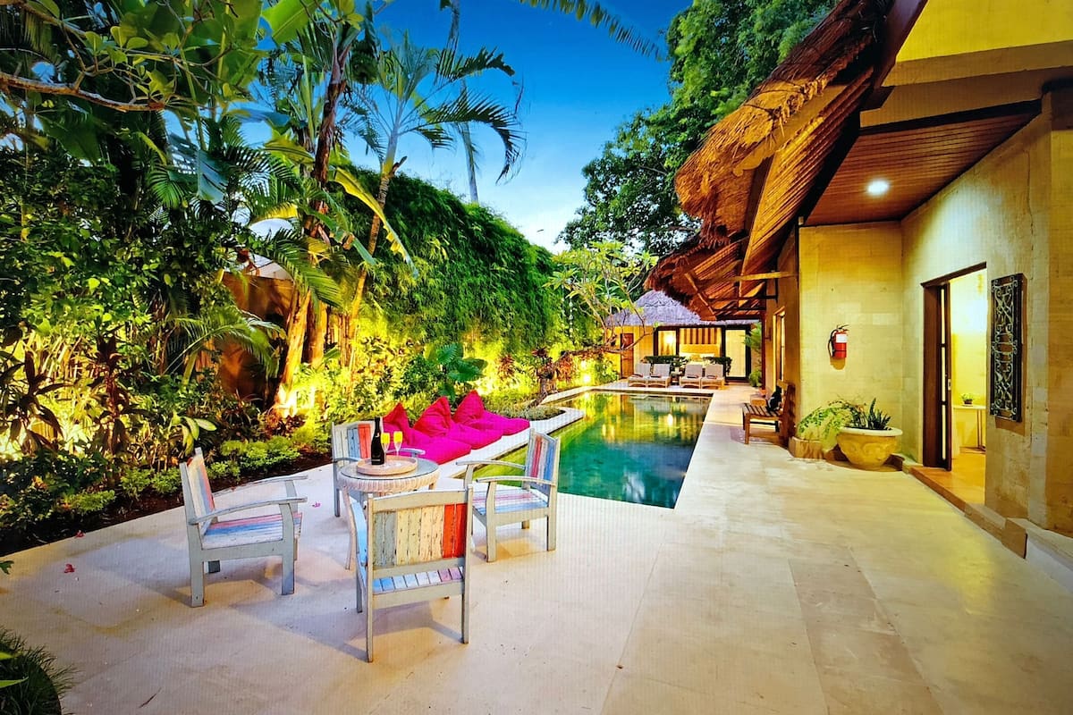 A poolside area with lounge chairs and a thatched-roof structure.