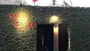 La entrada a Villa Elleo, con un letrero y dos banderas.