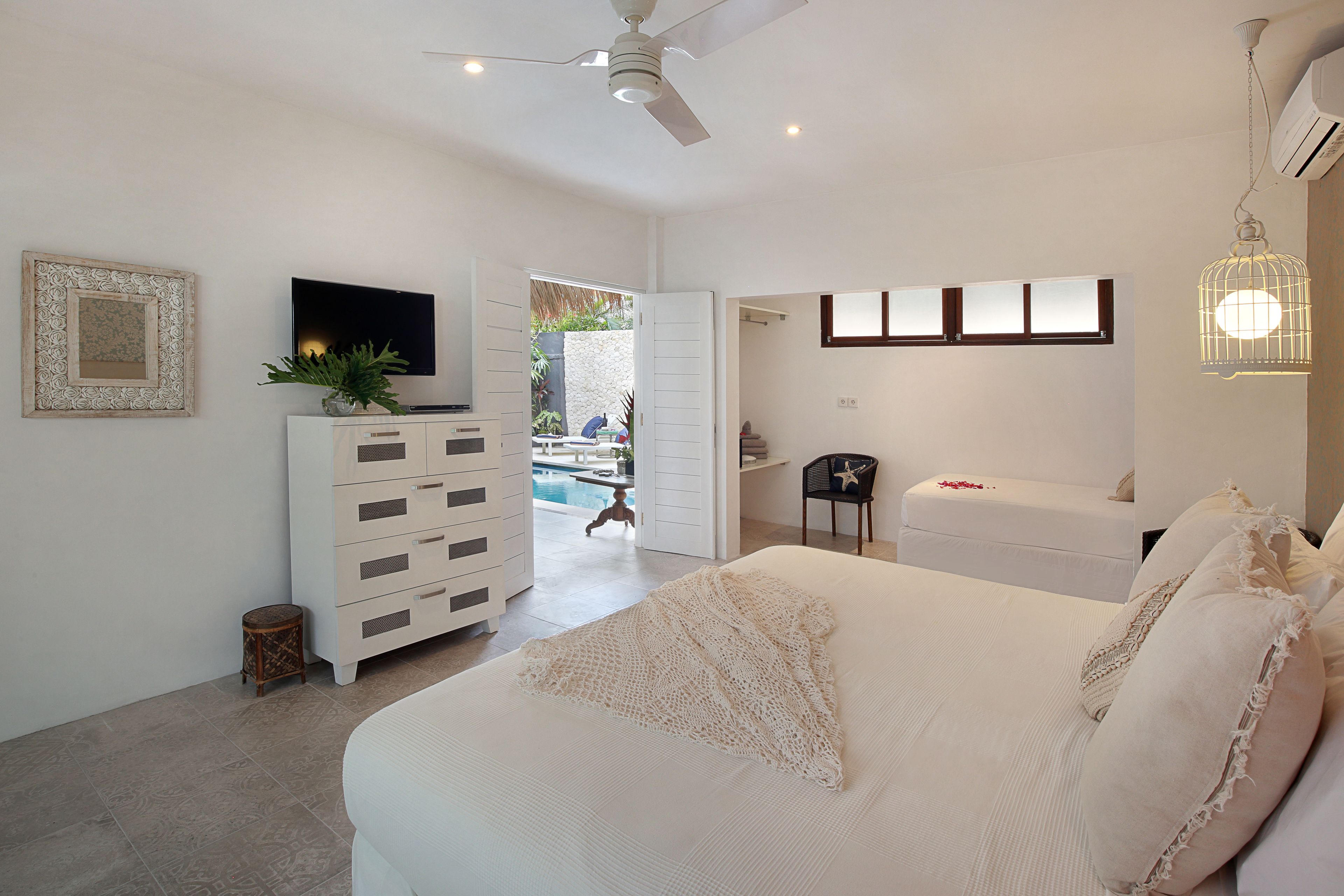 Una camera da letto con un letto, una TV, un comò e una ventola a soffitto.