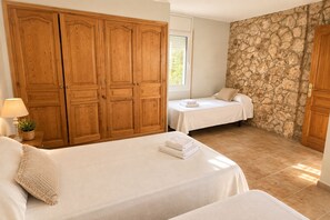 A bedroom with two beds, wooden wardrobe, stone wall, and a window. - Casa Winter Garden, popular with our regular guests (L'Ametlla de Mar)