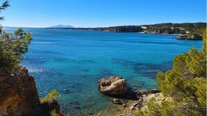 Paisaje costero con aguas azules cristalinas, costas rocosas y una montaña distante.