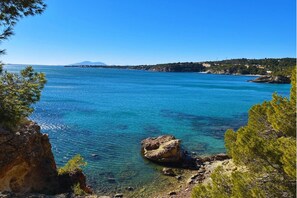 Paisaje costero con aguas azules cristalinas, costas rocosas y una montaña distante.