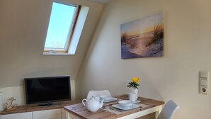 Ein Essbereich mit einem Tisch, Stühlen, einem Fernseher und einem Bild an der Wand.