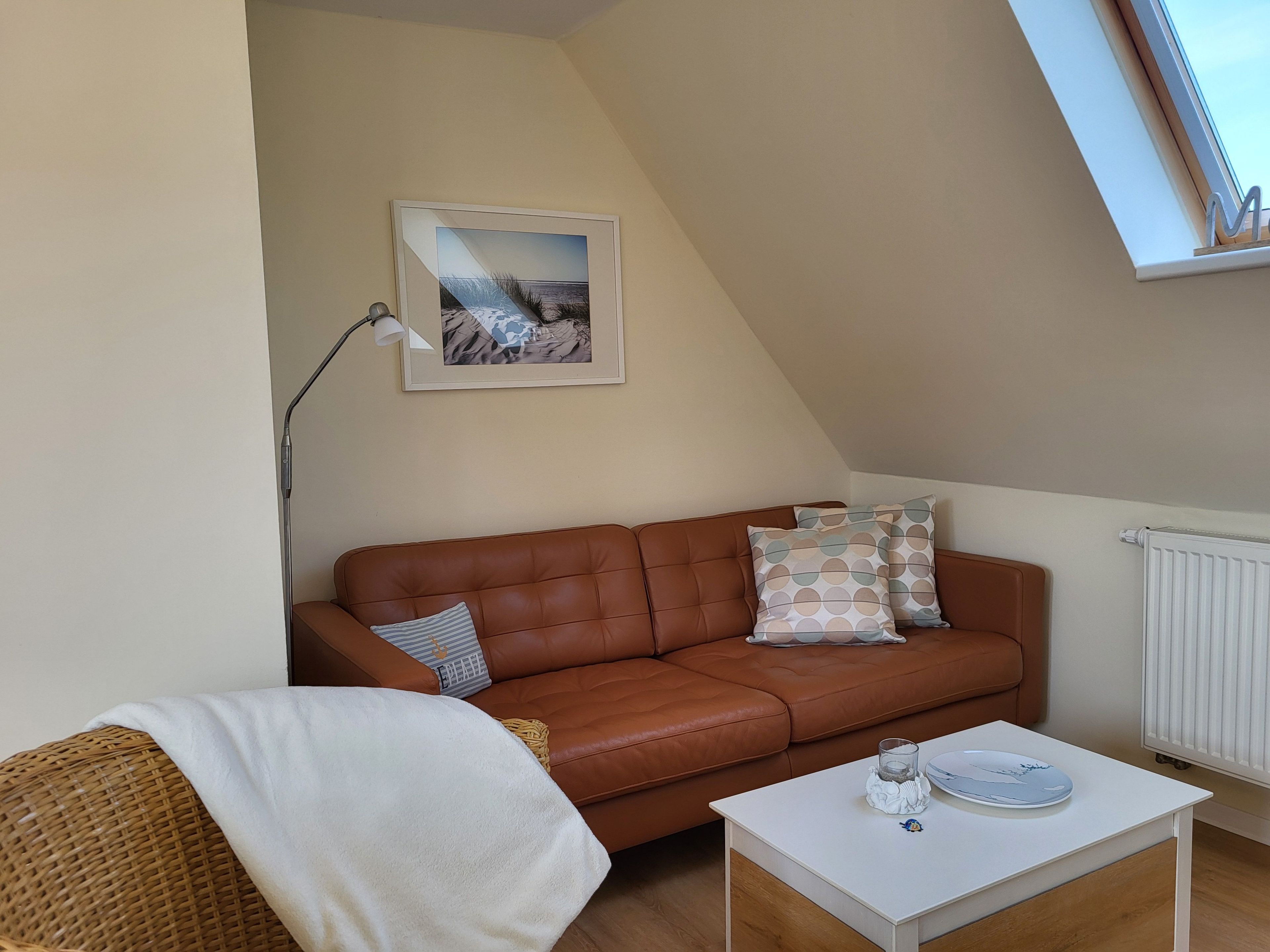 Quarto estilo loft aconchegante com um sofá de couro marrom, uma mesa branca e um quadro na parede.