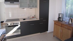 A modern kitchen with a built-in oven, a sink, and wooden cabinets.