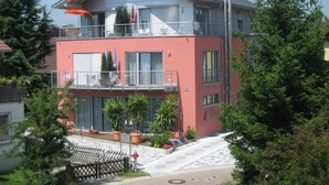 A two-story building with balconies, outdoor seating, and potted plants.
