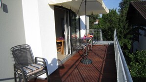 Ein Balkon mit Stuhl, Tisch und einem großen Sonnenschirm.