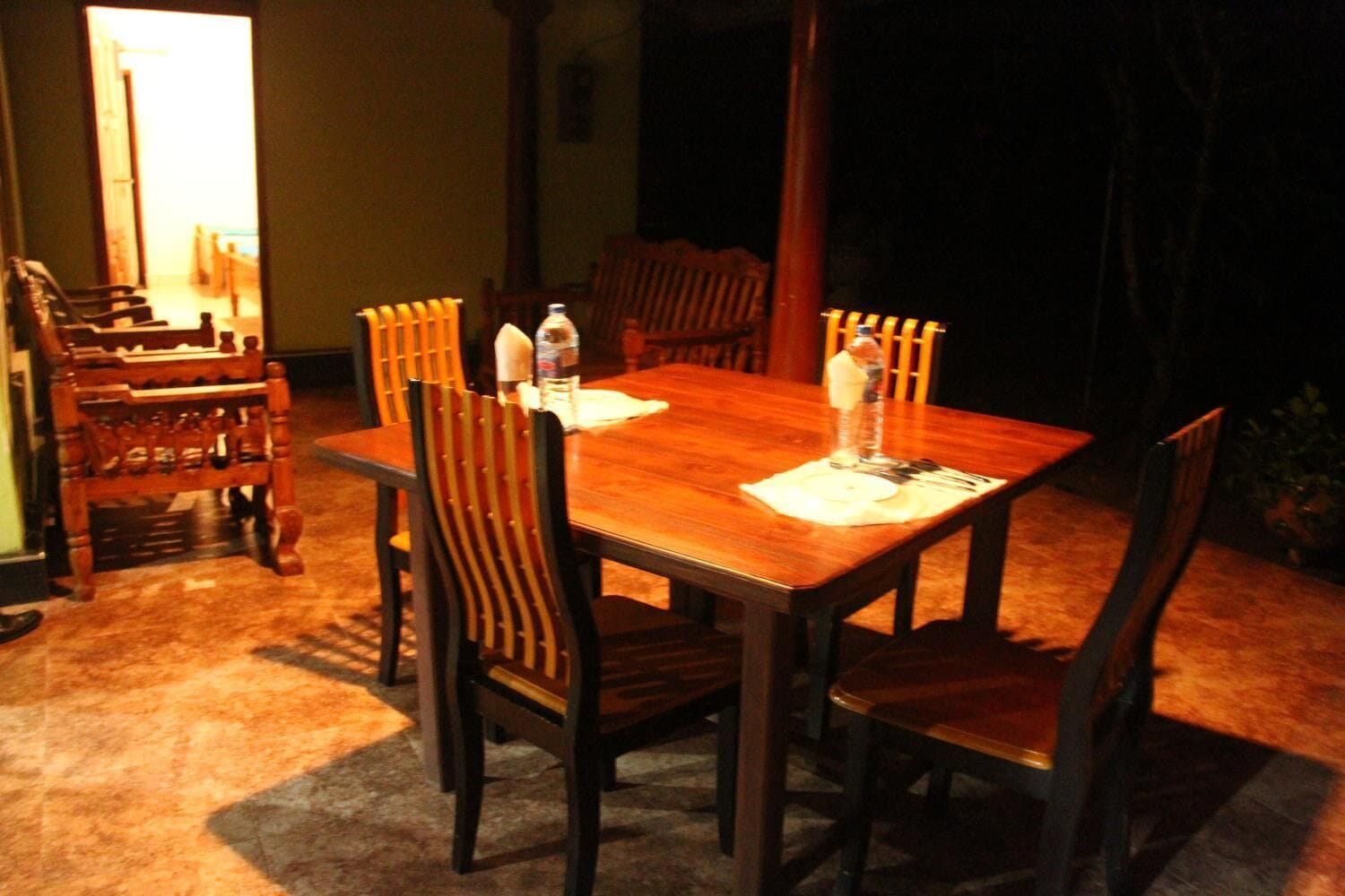 A dining area with a wooden table and chairs, a water bottle, and a bottle of hand sanitizer on the table.
