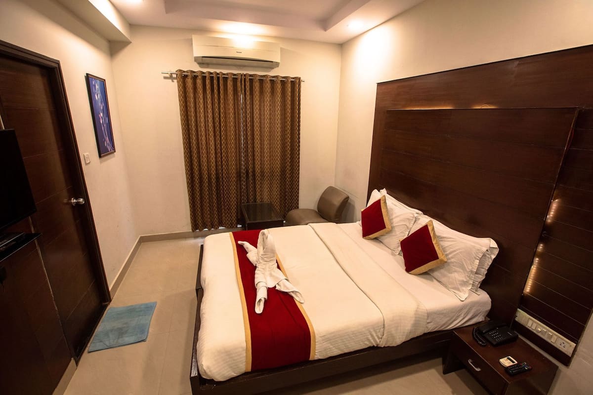 Une chambre d’hôtel équipée d’un lit, d’un bureau, d’une chaise, d’un climatiseur et d’un téléviseur.