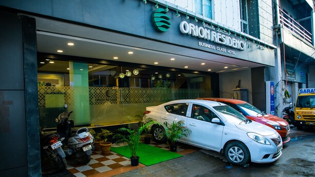 Entrada de hotel con un coche y una motocicleta estacionados afuera.