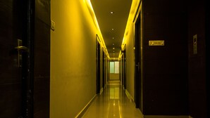 Un pasillo largo y estrecho con suelo y paredes reflectantes, que conduce a una puerta al final.