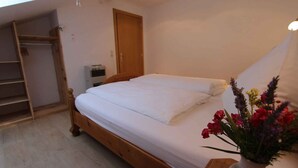 A bedroom with a wooden bed, a wardrobe, and a small air conditioning unit. - Holiday apartment mit Klimaanlage und Balkon (Maršići)