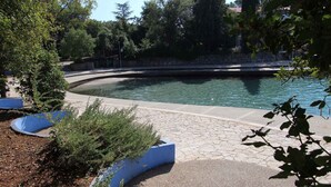 A swimming pool with a curved edge, surrounded by stone tiles and greenery. - Holiday apartment mit Klimaanlage und Balkon (Maršići)