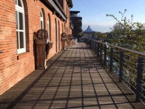 A brick building with a covered walkway and a railing. - Apartment / apartment 2 - Buxtepartment (Buxtehude)