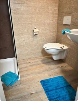 A small bathroom with a toilet, a sink, and a shower.