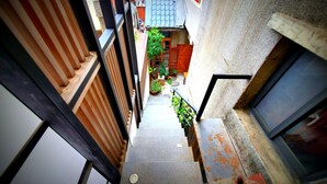 A narrow stairway leading to a small courtyard with potted plants and a wooden bench.