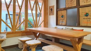 A wooden table with benches in a room with large windows and wooden beams.