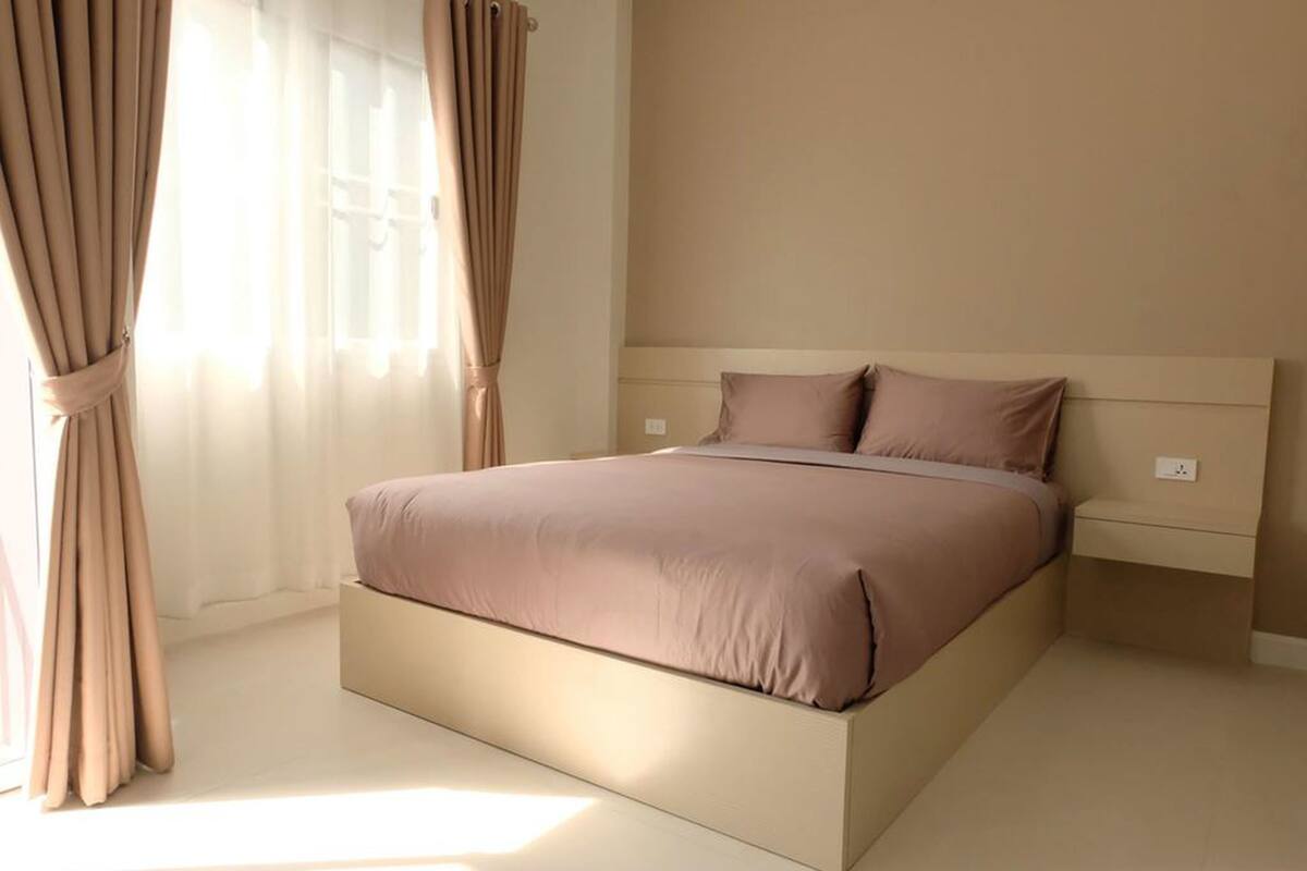 Une chambre moderne avec un grand lit, des rideaux beiges et une palette de couleurs neutres.
