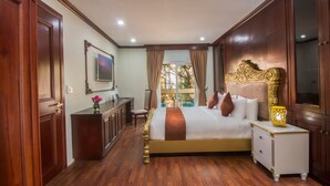 A spacious bedroom with a large bed, a desk, and a view of the outdoors. - Anachak Angkor Suite (Siem Reap)