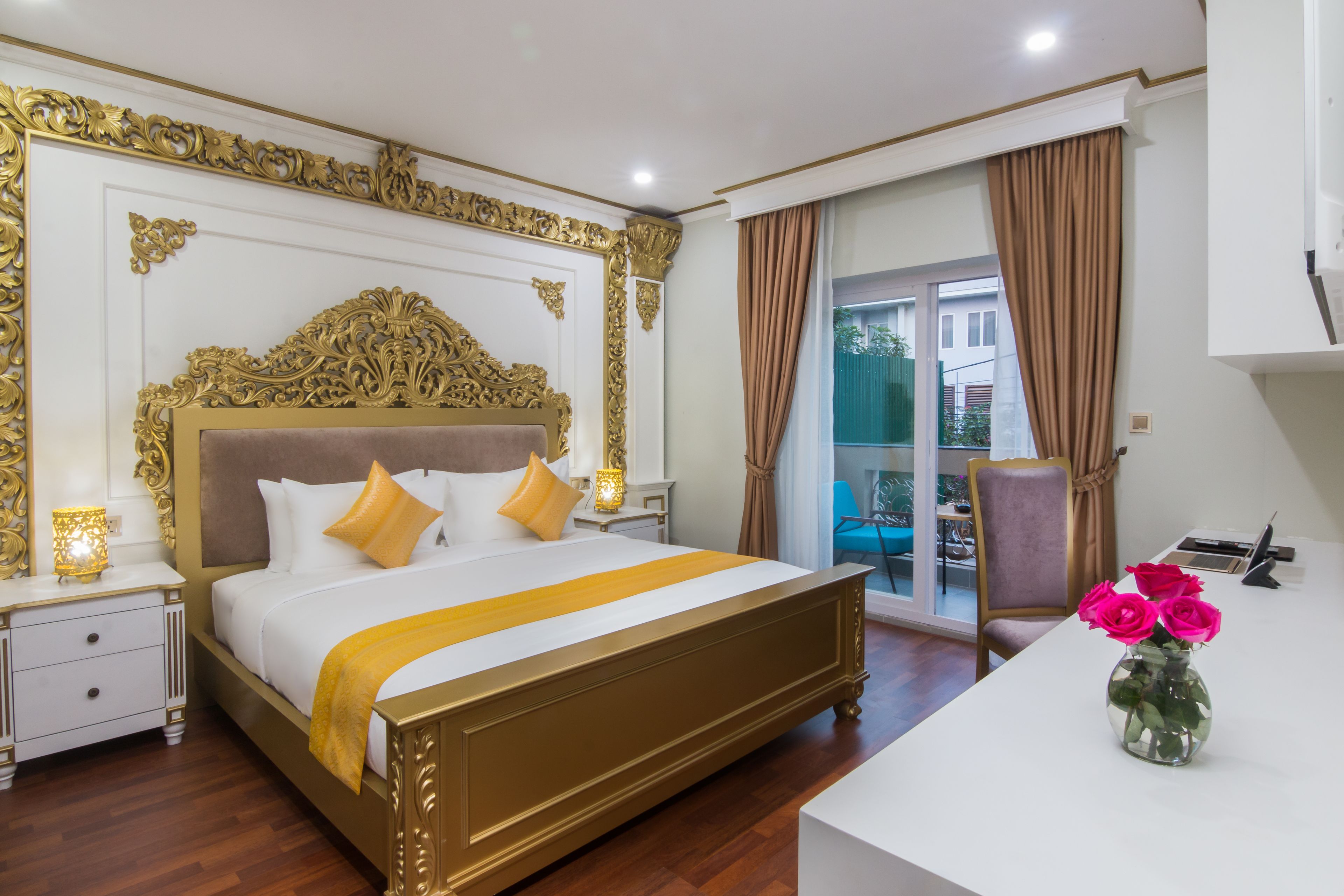 Une chambre d’hôtel avec un grand lit, un bureau et un vase de fleurs.