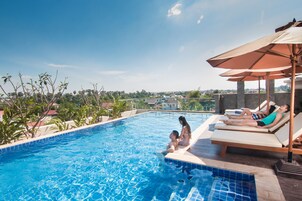 Una piscina al aire libre, sombrillas, sillones reclinables de piscina