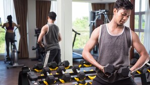 A gym with exercise equipment and a person lifting dumbbells. - Anachak Angkor Suite (Siem Reap)