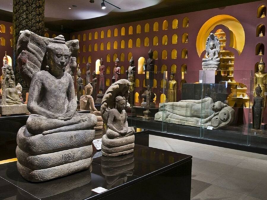 Interior de museo con esculturas de piedra y estatuas doradas en exhibición.